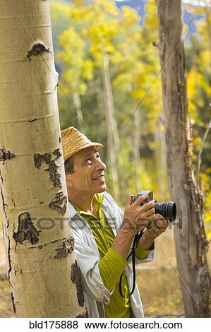 Man photographing with camera in autumn forest View Large Photo Image Stock Photo - Man photographing with camera in autumn forest. Fotosearch