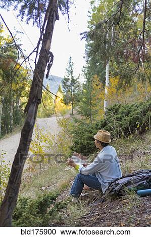 Stock Image - Man reading book on rural hillside. Fotosearch