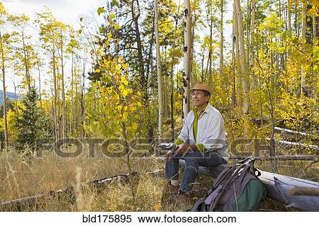 Stock Photography - Man sitting in autumn forest. Fotosearch