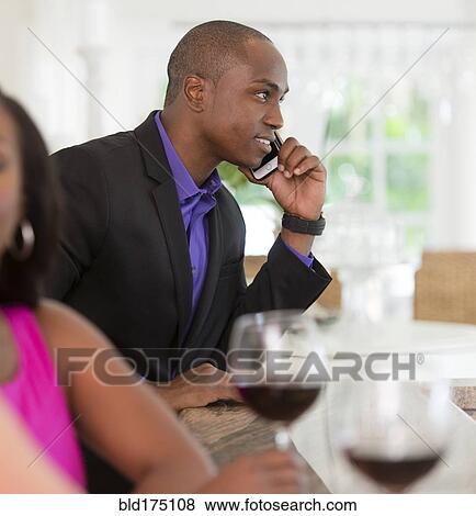 Stock Photo - Man talking on cell phone at wine bar. Fotosearch