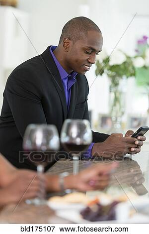 Stock Photo - Man using cell phone at wine bar. Fotosearch