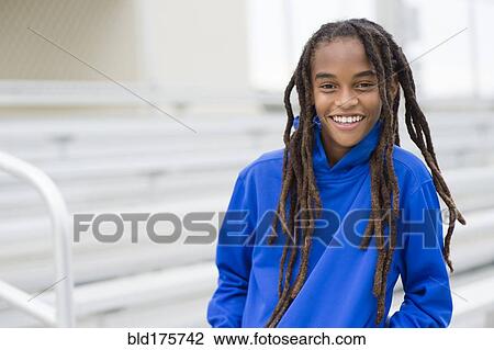 Stock Image - Mixed race boy smiling on bleachers. Fotosearch