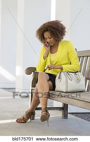 Stock Image - Mixed race businesswoman talking on cell phone. Fotosearch