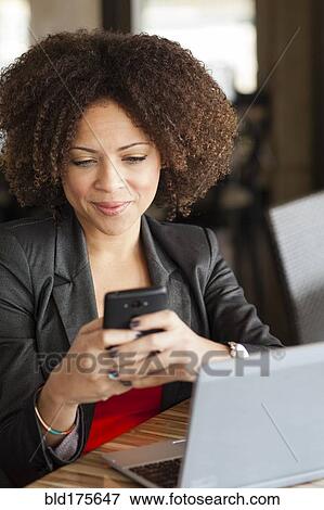 Stock Photo - Mixed race businesswoman using cell phone. Fotosearch