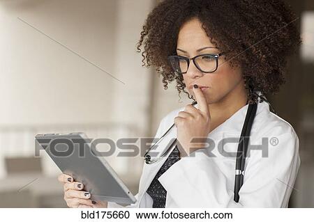 Stock Image - Mixed race businesswoman using digital tablet in office. Fotosearch