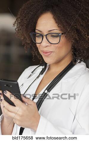 Stock Photo - Mixed race doctor using cell phone. Fotosearch