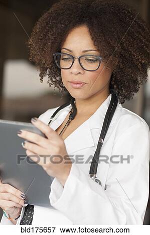 Mixed race doctor using digital tablet View Large Photo Image Stock Photo - Mixed race doctor using digital tablet. Fotosearch