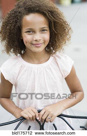 Stock Image - Mixed race girl smiling outdoors. Fotosearch