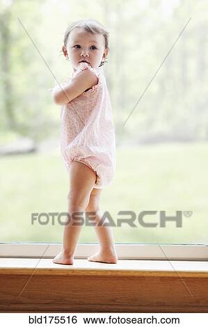 Stock Photograph - Mixed race girl standing at window. Fotosearch