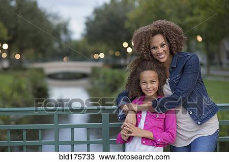 Mixed race mother and daughter hugging on bridge View Large Photo Image Stock Image - Mixed race mother and daughter hugging on bridge. Fotosearch
