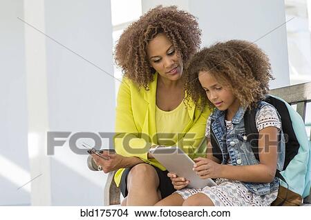 Mixed race mother and daughter using digital tablet View Large Photo Image Picture - Mixed race mother and daughter using digital tablet. Fotosearch