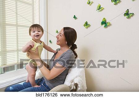 Stock Photograph - Mixed race mother holding baby daughter. Fotosearch