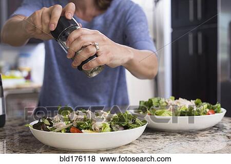 Stock Photo - Mixed race woman seasoning salad. Fotosearch