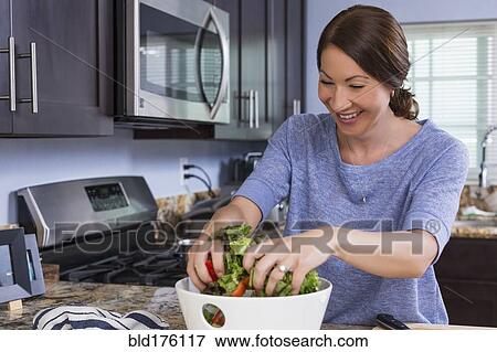 Mixed race woman tossing salad in kitchen View Large Photo Image Stock Photo - Mixed race woman tossing salad in kitchen. Fotosearch