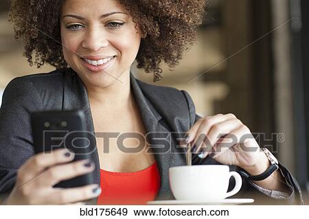 Mixed race woman using cell phone in cafe View Large Photo Image Stock Photo - Mixed race woman using cell phone in cafe. Fotosearch