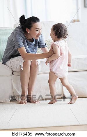 Stock Photography - Mother and baby daughter in living room. Fotosearch