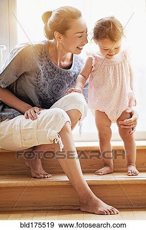 Stock Photo - Mother and baby daughter on steps. Fotosearch