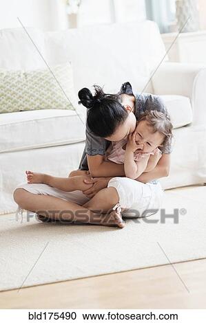 Mother and baby daughter playing in living room View Large Photo Image Stock Image - Mother and baby daughter playing in living room. Fotosearch