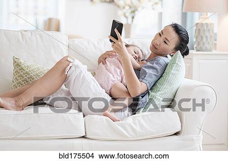 Picture - Mother and baby daughter using cell phone. Fotosearch