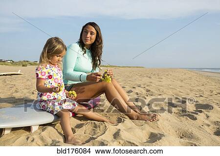 Picture - Mother and daughter eating grapes on beach. Fotosearch