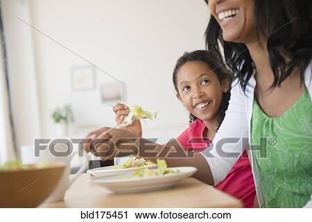 Stock Image - Mother and daughter eating salad. Fotosearch