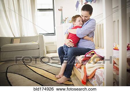 Stock Photograph - Mother and daughter hugging on bed. Fotosearch