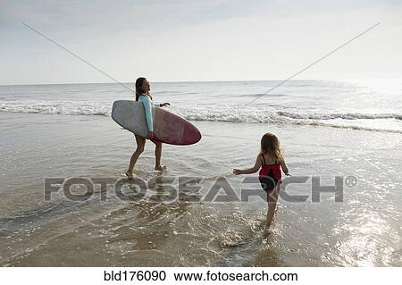 Mother and daughter playing in waves on beach View Large Photo Image Stock Image - Mother and daughter playing in waves on beach. Fotosearch