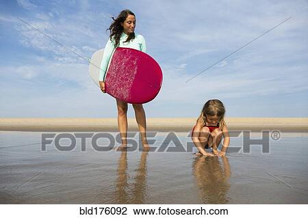 Mother and daughter playing in waves on beach View Large Photo Image Stock Image - Mother and daughter playing in waves on beach. Fotosearch