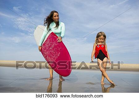 Stock Image - Mother and daughter playing in waves on beach. Fotosearch