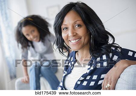 Stock Photo - Mother and daughter smiling on sofa. Fotosearch