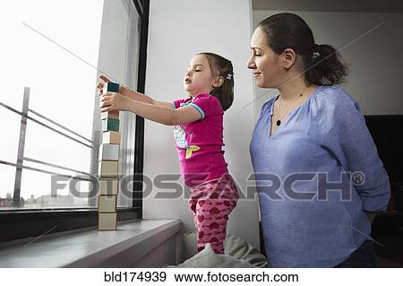 Stock Photo - Mother and daughter stacking blocks in window. Fotosearch