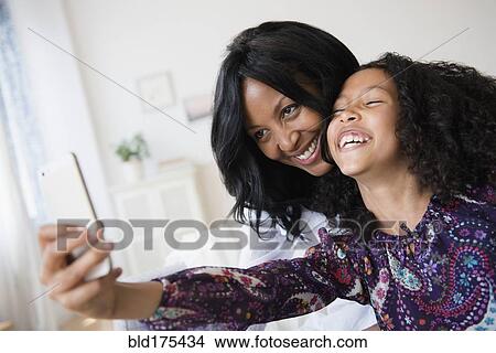 Picture - Mother and daughter taking selfie with cell phone. Fotosearch