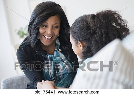 Stock Image - Mother and daughter talking on sofa. Fotosearch