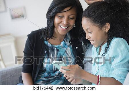 Mother and daughter using cell phone on sofa View Large Photo Image Stock Image - Mother and daughter using cell phone on sofa. Fotosearch