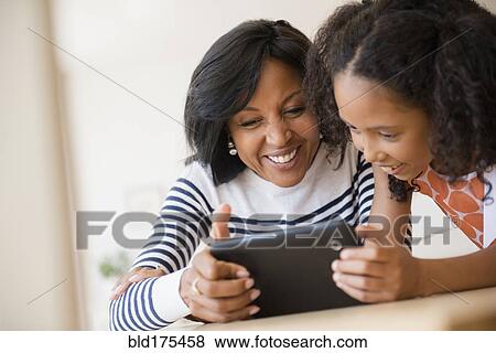 Mother and daughter using digital tablet View Large Photo Image Stock Photo - Mother and daughter using digital tablet. Fotosearch