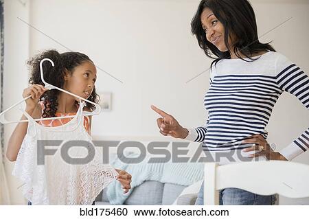 Stock Image - Mother disapproving shirt of daughter. Fotosearch