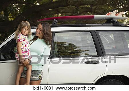 Mother holding daughter at car View Large Photo Image Stock Image - Mother holding daughter at car. Fotosearch
