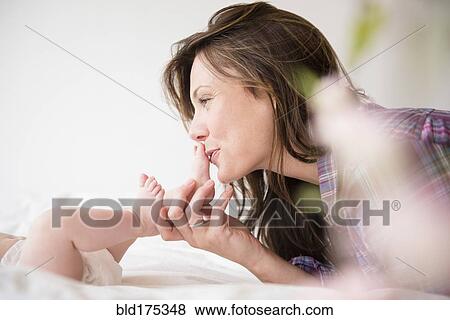Mother kissing feet of baby girl View Large Photo Image Stock Photo - Mother kissing feet of baby girl. Fotosearch