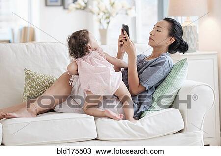 Stock Image - Mother photographing baby daughter. Fotosearch