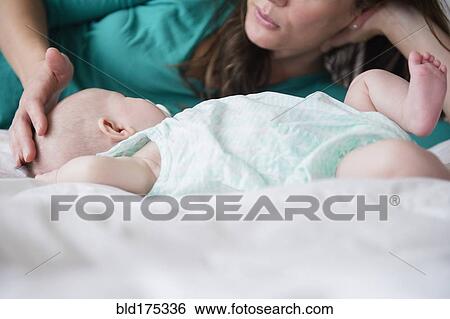 Stock Photograph - Mother playing with baby daughter. Fotosearch