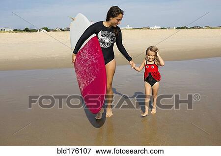 Mother teaching daughter to surf in ocean View Large Photo Image Stock Photo - Mother teaching daughter to surf in ocean. Fotosearch