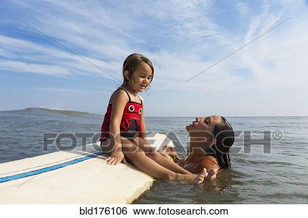 Mother teaching daughter to surf in ocean View Large Photo Image Stock Photograph - Mother teaching daughter to surf in ocean. Fotosearch