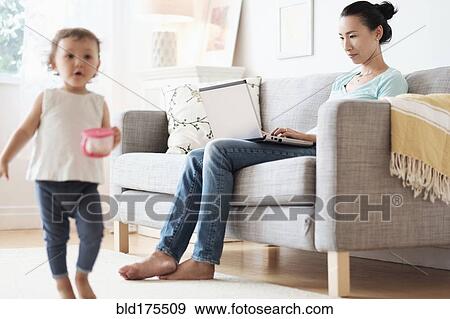 Mother using laptop ignoring baby daughter View Large Photo Image Stock Photo - Mother using laptop ignoring baby daughter. Fotosearch