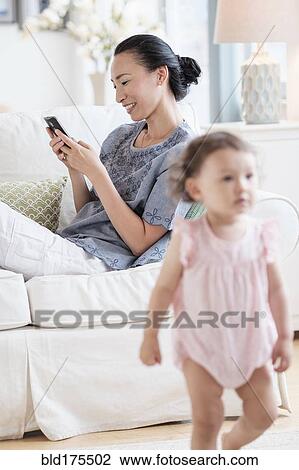 Stock Image - Mother with cell phone ignoring baby daughter. Fotosearch