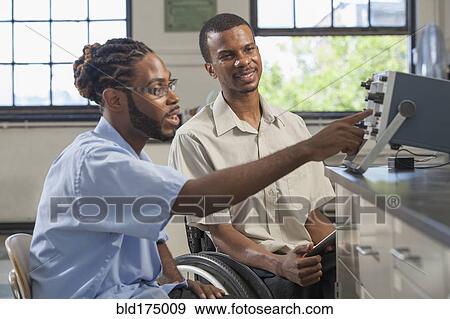 Stock Photo - Paraplegic student and classmate working in science classroom. Fotosearch