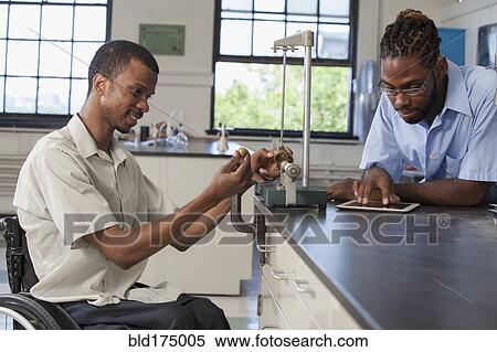 Stock Photography - Paraplegic student and classmate working in science classroom. Fotosearch