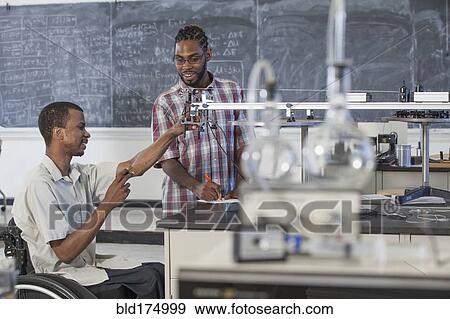 Stock Photo - Paraplegic student working with classmate in science classroom. Fotosearch