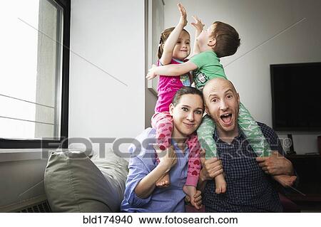 Stock Image - Parents carrying children on shoulders. Fotosearch