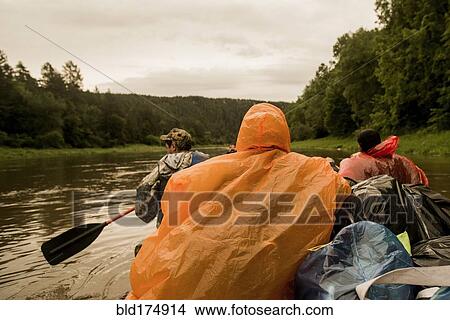 Picture - People wearing ponchos on boat in river. Fotosearch