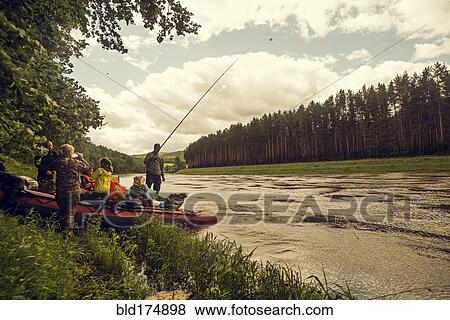 Stock Photo - People with boat fishing on riverbank. Fotosearch